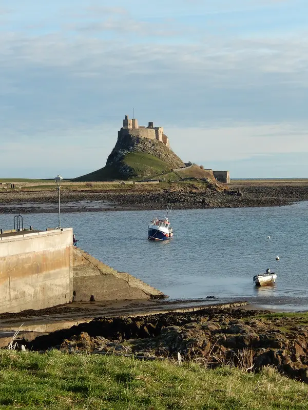 Castle on a hill with sea and boats in front