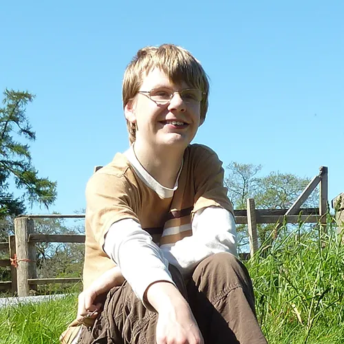 Me aged fourteen sitting on a grassy hillside